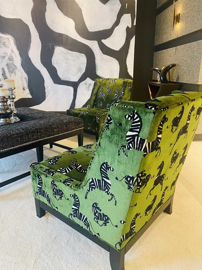 Green shiny upholstered armless chair with zebra prints against the green fabric